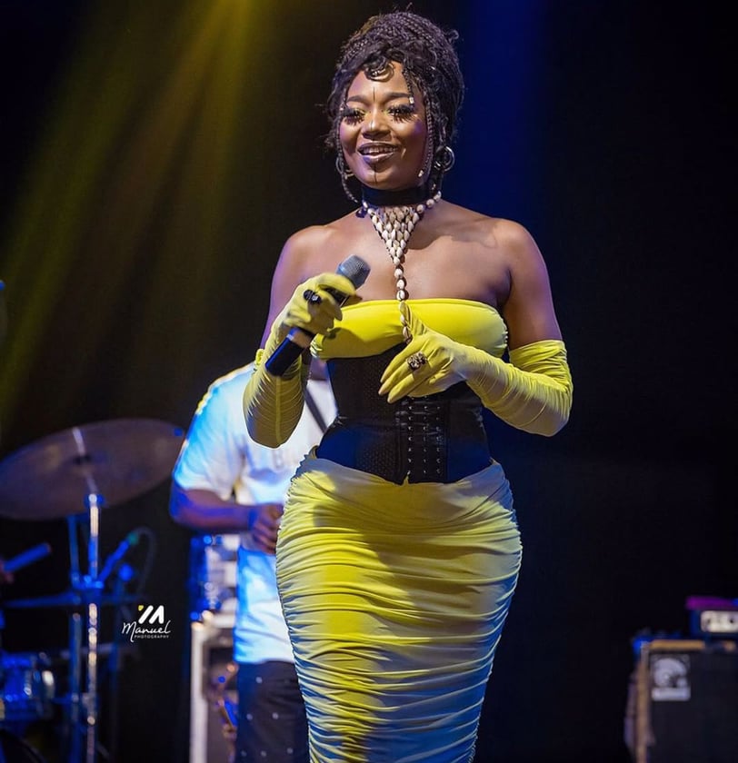 Efya Nocturnal looking stunning on stage in a bright yellow dress.