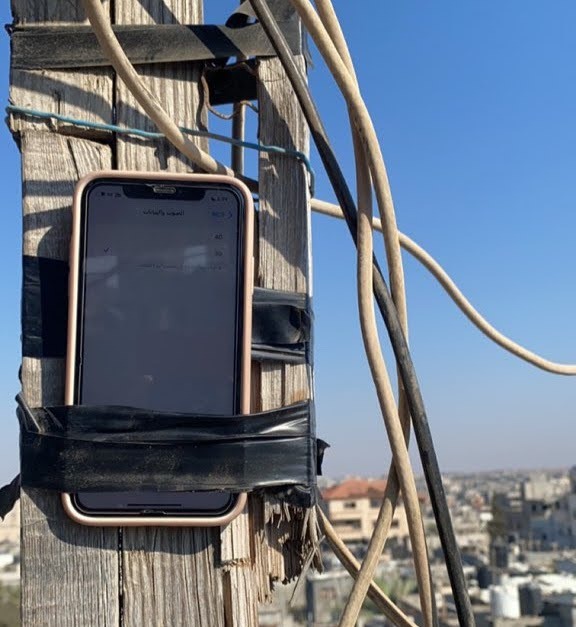 Palestinians hang a phone in a high place in an attempt to catch an internet signal.