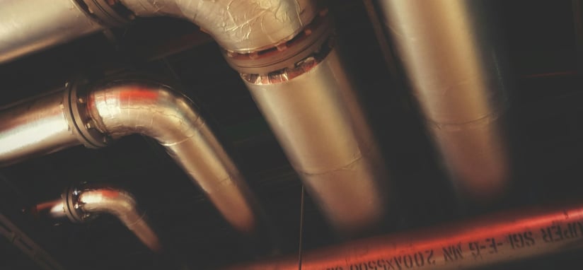 Network of insulated silver pipes on a ceiling.