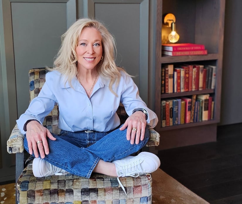 a blonde woman sitting in a chair in a home library
