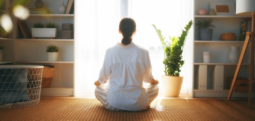 a woman sitting on the floor and looking out the window