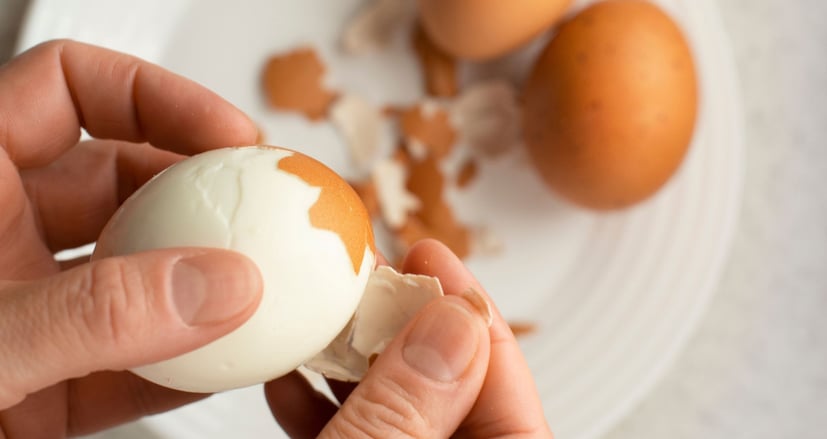 someone peeling a hard boiled egg