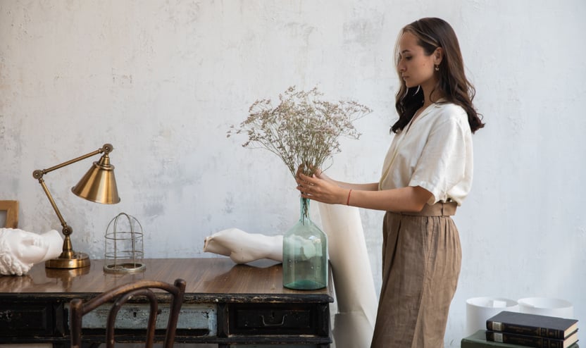 a woman putting dried foliage into a vase