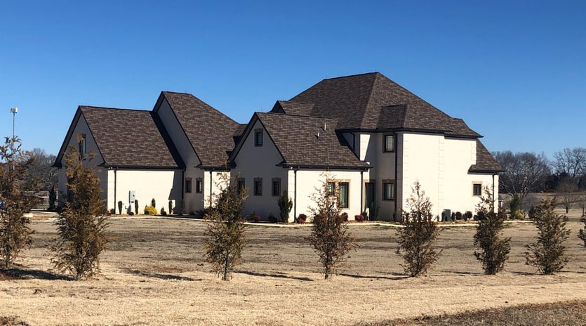 A new home designed by Veteto Design | Newly constructed large home with a blue sky and small trees