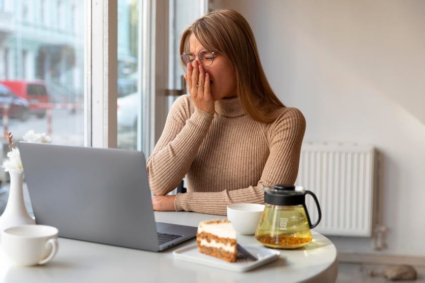 a woman sitting at a table with a laptop and a cup of coffee