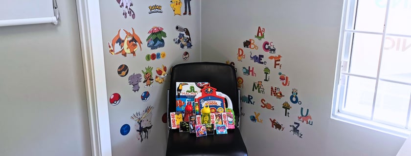 Picture of consult room with stickers on the wall and a chair filled with children's items
