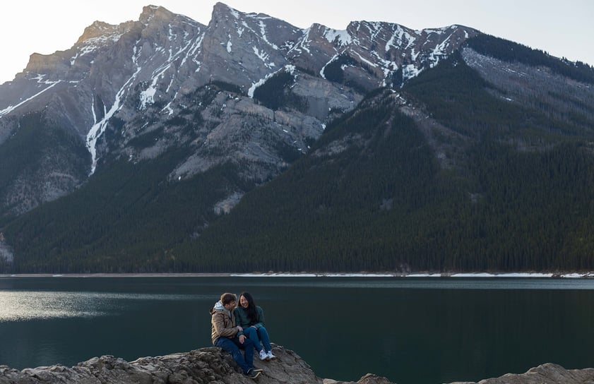 a couple sitting on a rock formation at lake minnewanka in Banff 