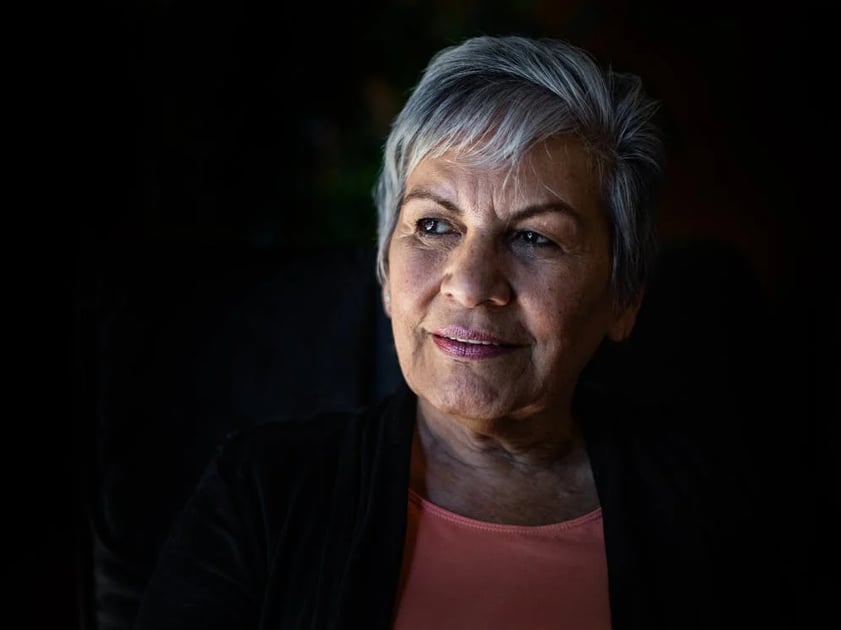 a woman with grey hair and a pink top