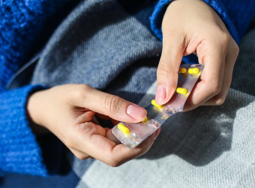 a person holding a small plastic container with a yellow and blue nail polish