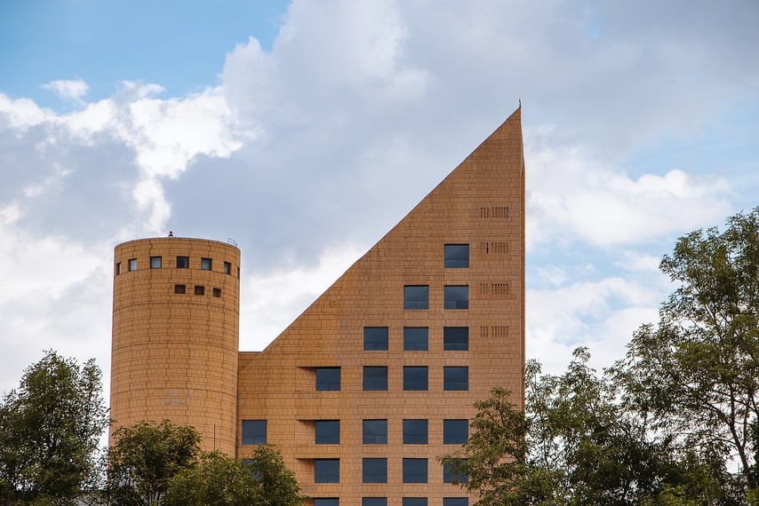 image of a tall brick building with a triangle shaped roof and a castle tower next to it