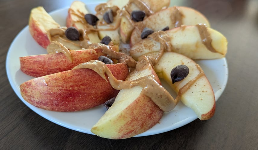 Apple slices made into a dessert nacho with peanut butter drizzle, chocolate chips and cinnamon