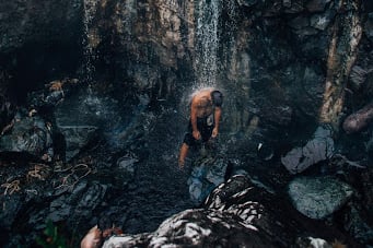 Man washing under waterfall
