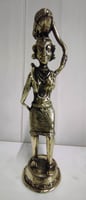 "Brass statue of a woman in attire carrying a pumpkin on her head and tools on her shoulder-For international dispatch