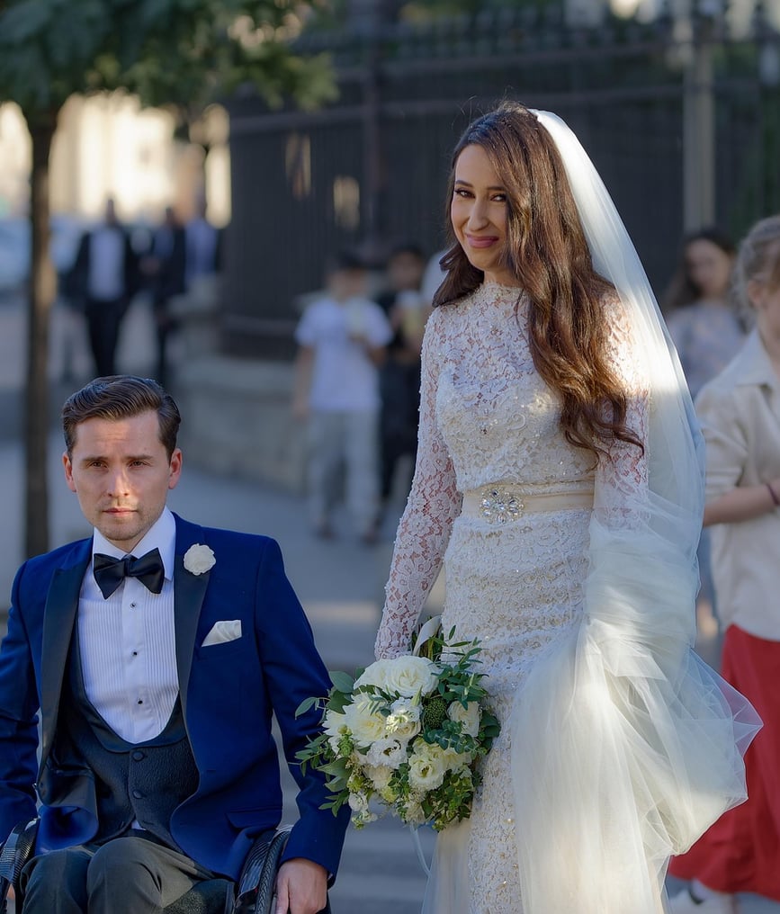 A man in a wheel chair on his wedding day with his bride.