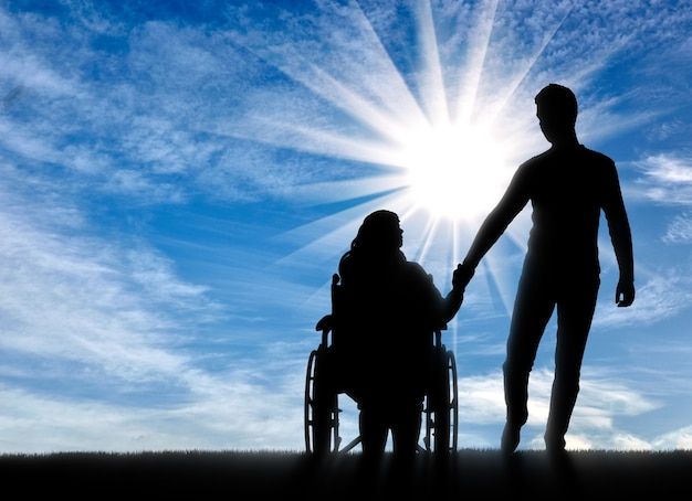 um homem e uma mulher de mãos dadas em uma cadeira de rodas