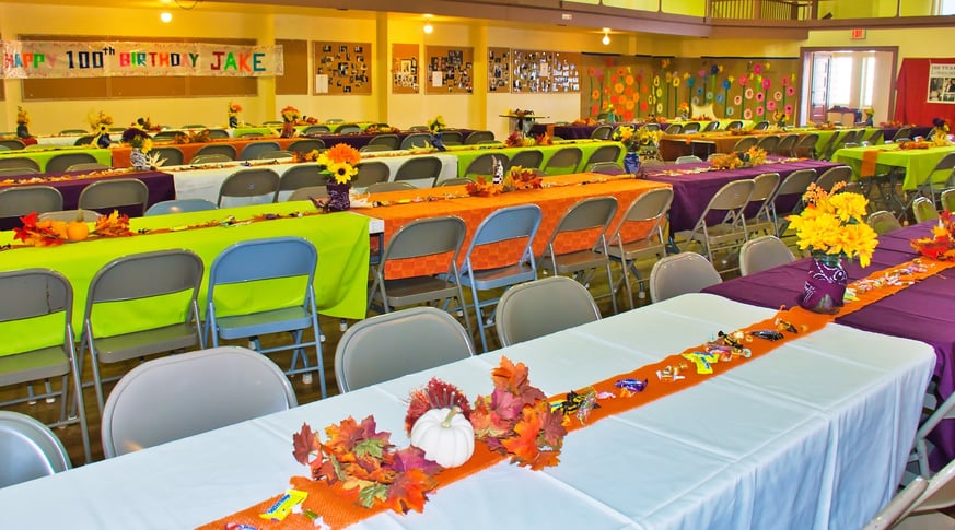 a large room with decorated tables and chairs with a birthday celebration banner