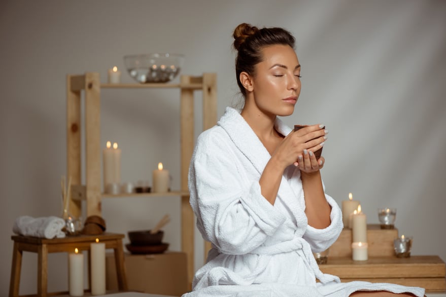 Woman relaxing with tea and candles, enjoying a peaceful moment.