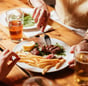 foto di un piatto di carne succulento con patatine fritte e delle birre. Scena di life style