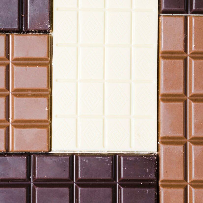 Top view of white, milk & dark chocolate bars squared together like Lego pieces with break lines