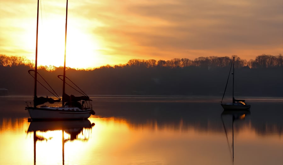 a sailboat is shown in the foreground of a sunset
