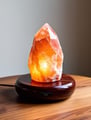 Soft glowing salt lamp with dimmer switch on a wooden tray