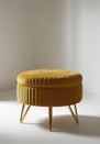 Butter yellow velvet ottoman with ribbed texture and gold legs, minimal and elegant.