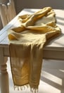 Yellow cheesecloth table runner draped over a light wooden table.