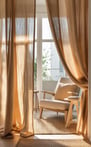 A sheer linen curtain softly sections off a cozy reading nook in a sunlit apartment.