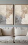 Pair of neutral-toned abstract canvas prints above a light beige sofa.