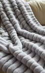 Striped grey throw blanket draped over a beige couch.