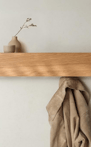 A compact wooden wall shelf with hooks underneath, blending storage and display.