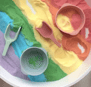 a bowl of colored sand with a spoon and spoon