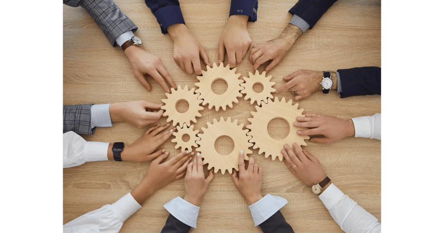 Hands of diverse professionals collaborating to connect wooden gears, symbolizing teamwork