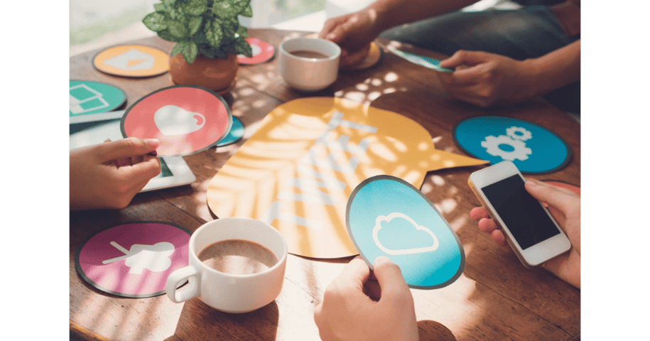 Team collaboration concept with hands holding social media icons around a table, symbolizing digital