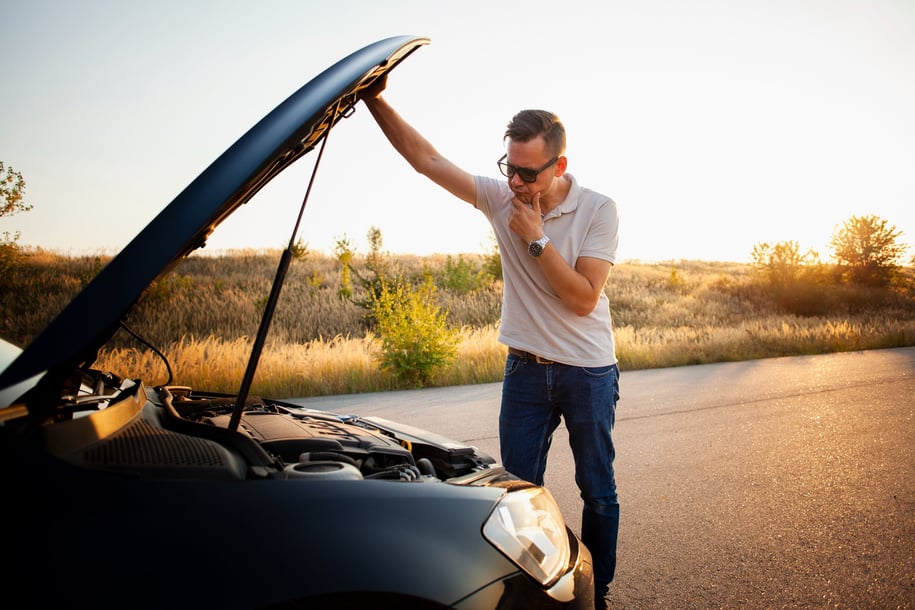 a man standing in front of a car with a broken hood