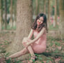 a woman sitting on a tree stump in a park