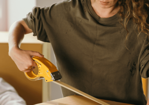 a women packing box with tape