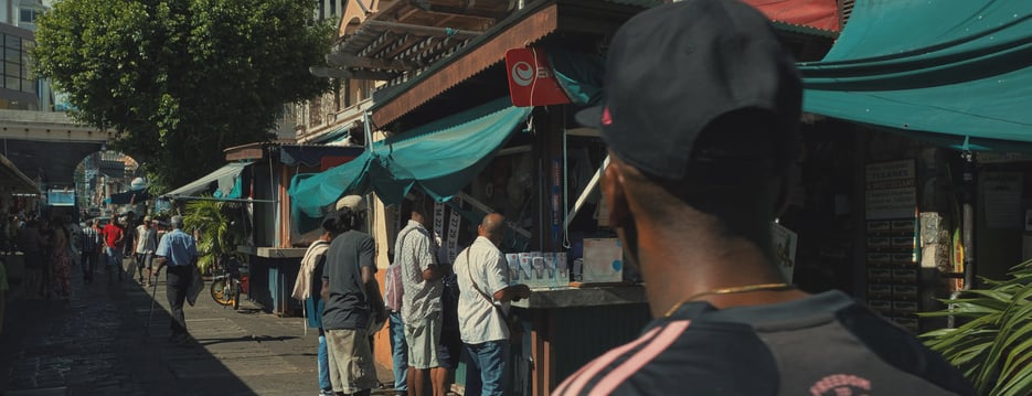 Street photography scene showing daily life outside food stalls at the Central Market in Port Louis, Mauritius