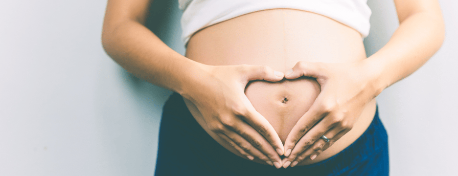 Coeur avec les mains sur le ventre d'une femme enceinte