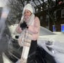 a woman in a pink coat and scarf on a snowy day