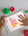 a child's hands on a tablet with dice