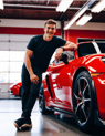 a young man smiles happily next to his sports car after receiving top-notch service at AMI Service