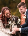 a bride and groom pose with their dog for a photo