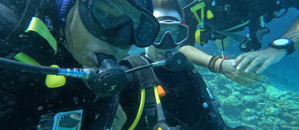 Content creator couple snorkeling with GoPro surrounded by colorful coral reef at Menjangan Island, Bali