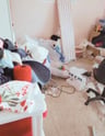 Cluttered craft room filled with boxes, crafting supplies, and disorganised items.