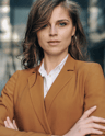a woman in a brown jacket and white shirt