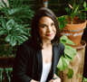 Woman looking at camera, posing in front of plants. 