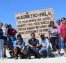 a group of people standing around a sign that says magnetic hill