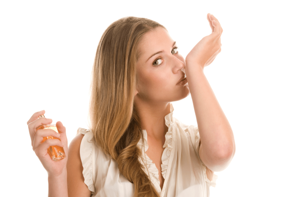 mujer oliendo perfume en su muñeca