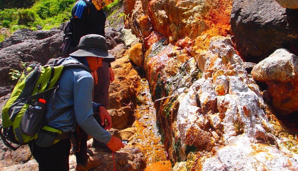 two people standing on rocks with a backpack